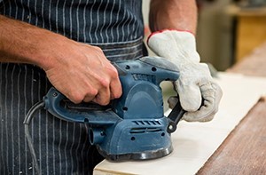 Image of a worker using a sander on a piece of wood
